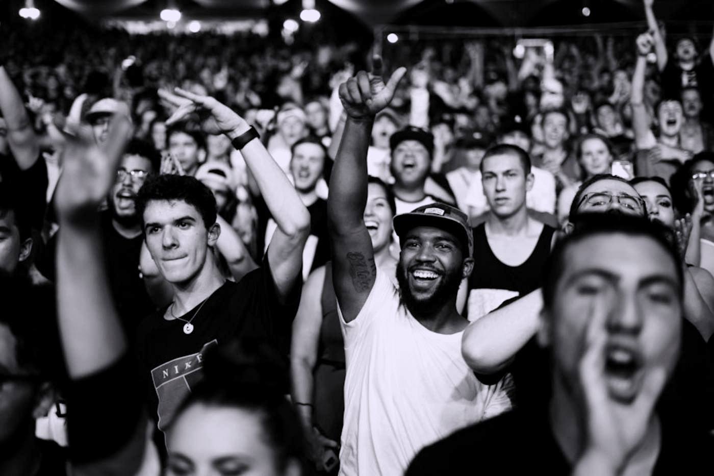 A crowd at a concert, singing and cheering towards the stage.