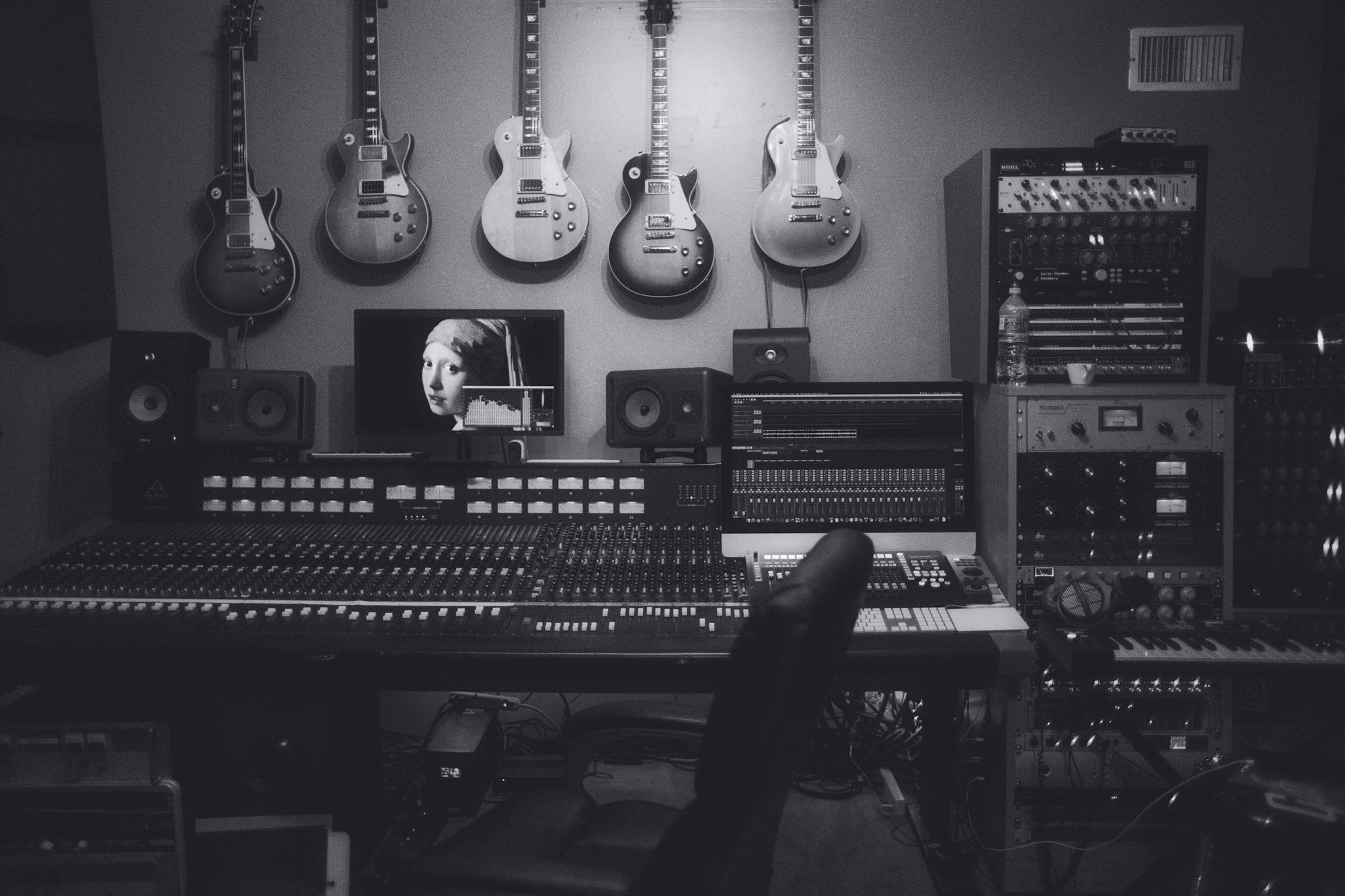 A recording studio at night: guitars on the wall above a mixing desk.